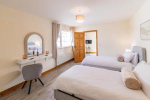 a bedroom with two beds and a desk and a mirror at Hillside House - Rose Cottage in Ballinamuck