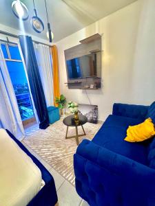 a living room with a blue couch and a table at Sunstone Studio- Ngong Rd Near Junction Mall in Nairobi