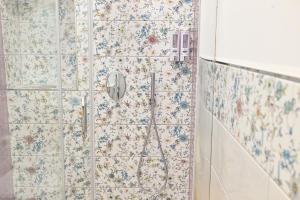 a shower in a bathroom with floral wallpaper at Lucia Appartamenti in Ischia Town