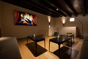 two tables in a living room with a fire painting on the wall at Badiula in Carlentini