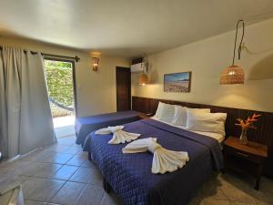 two beds in a hotel room with towels on them at Hotel Pousada Imbassai in Imbassai