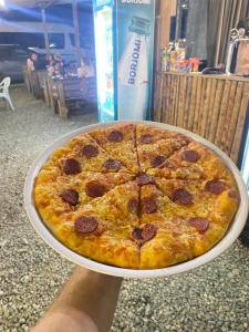 a person holding a pizza on a plate at Barakat Hotel in Ureki