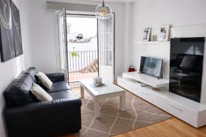 a living room with a black leather couch and a tv at ático con terraza- solarium in Écija