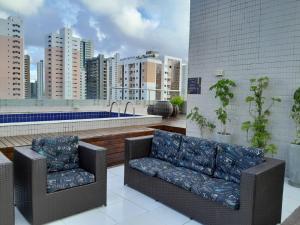 zwei Stühle und eine Couch auf einem Balkon mit Blick auf die Stadt in der Unterkunft Murano Suits Hotel in João Pessoa