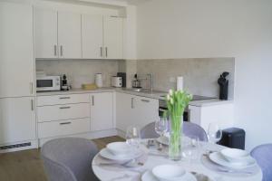 a kitchen with a table with chairs and white cabinets at Modernes Apartment in Schwechat in Schwechat