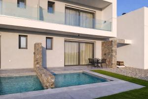a house with a swimming pool in front of it at Haraki Emerald in Haraki