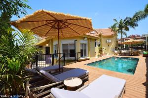 a patio with an umbrella and a swimming pool at וילה ארבל in Kefar Weradim