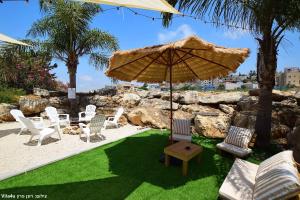 a patio with a table and chairs and an umbrella at וילה ארבל in Kefar Weradim