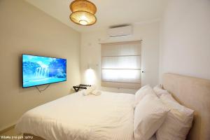a bedroom with a white bed and a flat screen tv at וילה ארבל in Kefar Weradim +38 photos