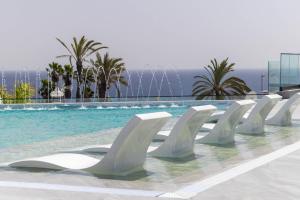 a row of white chairs sitting next to a swimming pool at Hotel Royal Atlántico in Puerto del Carmen