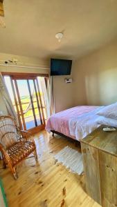 a bedroom with a bed and a chair and a window at Vale de Cambara in Cambará
