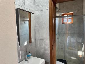 a bathroom with a sink and a shower with a mirror at Vale de Cambara in Cambará