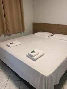 a white bed with two towels on top of it at Hotel Sara - Ampere in Ampère