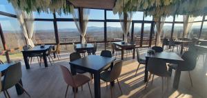 a restaurant with tables and chairs and a large window at Хотел Магура in Rabisha