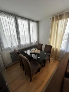 a dining room with a table and chairs and windows at apartment with balcony in Ronchin
