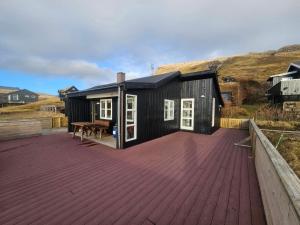 a black house on a wooden deck with a table at Mulheidar in Leynar
