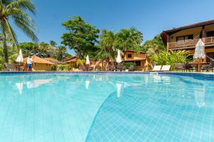 a swimming pool at a resort with a woman walking by at Hotel Pousada Imbassai in Imbassai