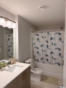 a bathroom with a toilet and a shower curtain with dolphins at Cozy and comfortable in Calgary +14 photos