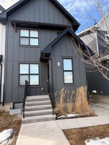 a gray house with a black door and stairs at Cozy and comfortable in Calgary