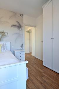a bedroom with a white bed and a wall with palm trees at Lora Luxury Suite 6 ,free private parking, self check in, air conditioner in Como