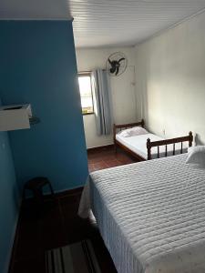 a bedroom with a white bed and a window at Refugio Caiçara in Cananéia