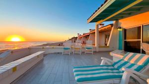 a balcony with chairs and the ocean at sunset at Cozy & Colorful Beachfront Condo Las Olas I 28 in Puerto Peñasco