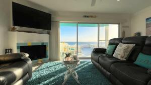 a living room with a leather couch and a television at Cozy & Colorful Beachfront Condo Las Olas I 28 in Puerto Peñasco
