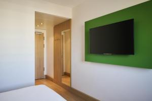 a bedroom with a television on a green wall at NH Ludwigsburg in Ludwigsburg