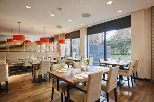 a dining room with tables and chairs and windows at NH Ludwigsburg in Ludwigsburg