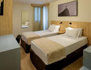 a hotel room with two beds and a mirror at Rio Hotel by Bourbon Batel - Curitiba in Curitiba