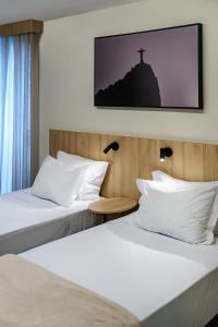 two beds in a hotel room with a cross on the wall at Rio Hotel by Bourbon Batel - Curitiba in Curitiba +22 photos