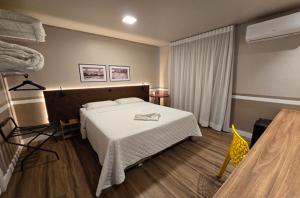 ein Schlafzimmer mit einem großen Bett und einer weißen Decke in der Unterkunft Hotel Nelo in Jaraguá do Sul