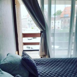 a bedroom with a bed and a large window at Les Remparts in Antoing