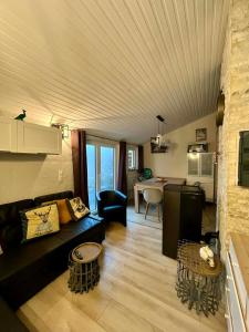 a living room with a black couch and a kitchen at Chalet de la fée Marion et Alice in Virton