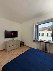 a bedroom with a bed and a tv and a window at Spazioso appartamento 2 in Tortona