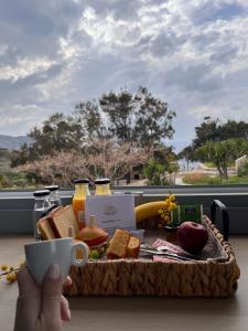a person holding a cup of coffee and a tray of food at Chrysonisos Suites with Sunset & Seaviews near Kini in Ano Syros