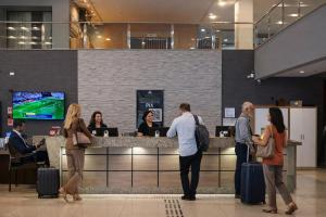 a group of people standing at a counter with luggage at Hotel Thomasi Express in Maringá