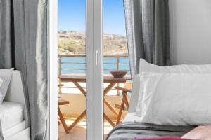 a bedroom with a bed and a balcony with a table at Haraki Aqua Marine in Haraki