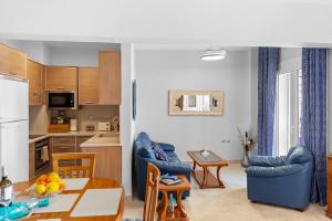 a kitchen and living room with blue chairs and a table at Haraki Aqua Marine in Haraki +4 photos