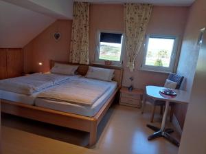 a bedroom with a bed and a desk and two windows at Pension Kölzer in Mörsdorf