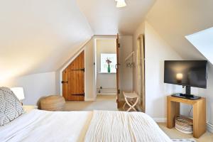 a bedroom with a bed and a flat screen tv at Plum Pudding Stables by Bloom Stays in Faversham