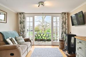 a living room with a couch and a sliding glass door at Plum Pudding Stables by Bloom Stays in Faversham