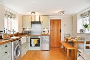 a kitchen with white cabinets and a wooden table at Plum Pudding Stables by Bloom Stays in Faversham