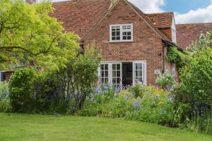 a brick house with flowers in the yard at Plum Pudding Stables by Bloom Stays in Faversham