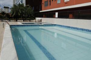 a large swimming pool with blue tiles on a building at Apto novo com ampla sacada e piscinas in Guarujá