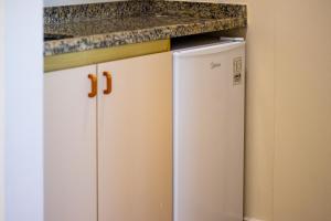 a kitchen with a white refrigerator and a counter at Maktub Hotel Itu in Itu