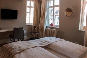 a bedroom with a bed and a desk and windows at Quartier im Eltvinum in Eltville