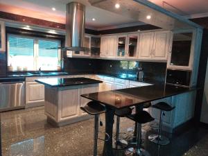 a kitchen with white cabinets and a island with bar stools at Casa Flamingo in Viseu