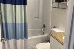 a bathroom with a white toilet and a shower curtain at Salty Paws II in Kill Devil Hills +20 photos
