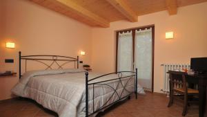 a bedroom with a bed and a desk and a window at Agriturismo Cascina Prato in Cravanzana
